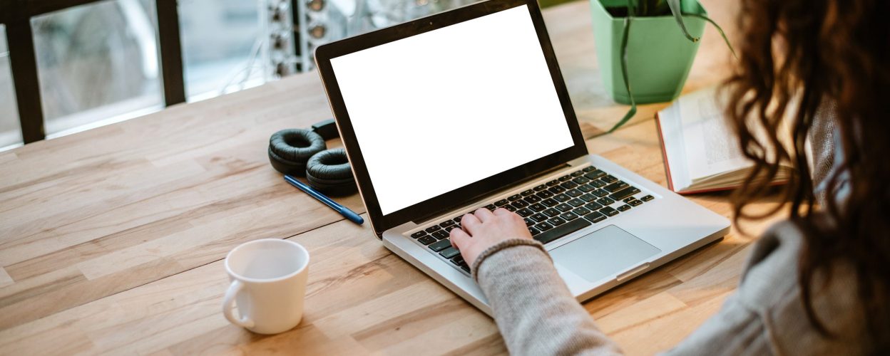 Woman working on laptop with white screen in modern office.